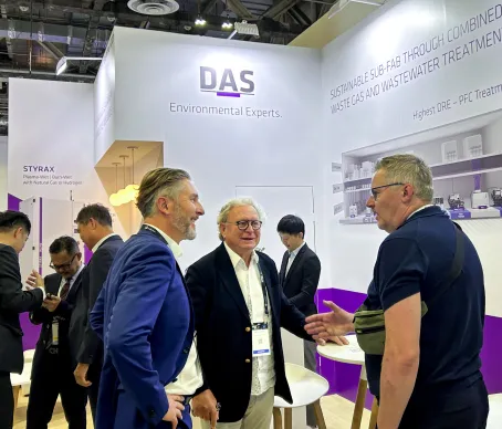Booth at a trade show with a group of visitors in discussion with a vendor